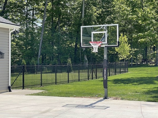 Black fence around a large yard with a basketball hoop