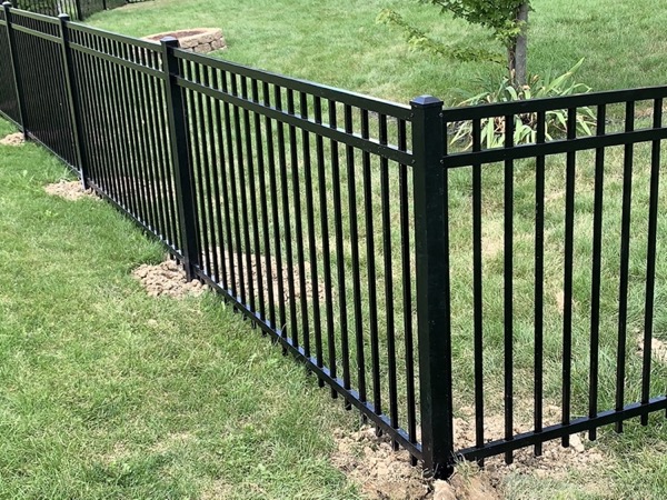 A black aluminum fence along a green lawn