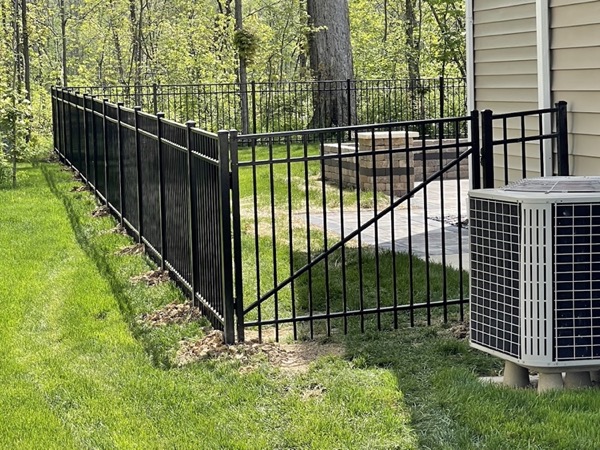 A black aluminum gate set into a fenced garden