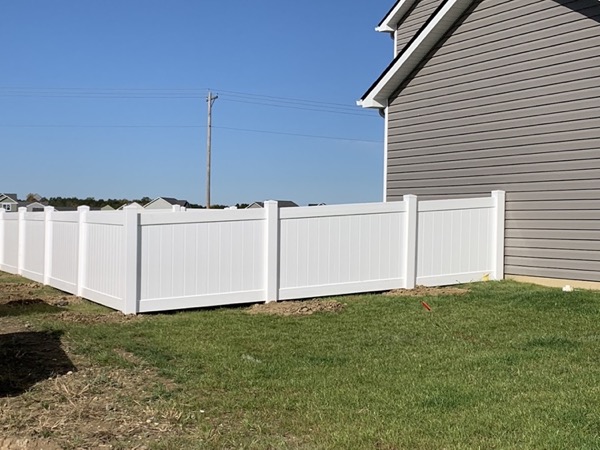 A white vinyl privacy fence along a lawn