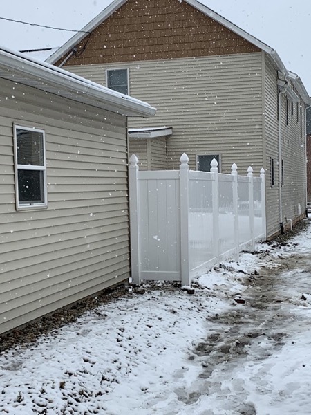 A white vinyl privacy fence beside a house
